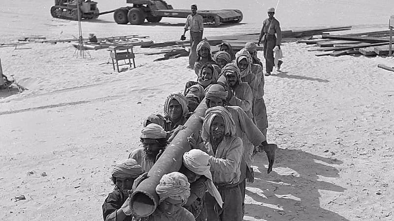 عمال حفر أثناء نقل أنبوب إلى أحد منصات حفر آبار النفط قبل 77 عاماً .. صورة